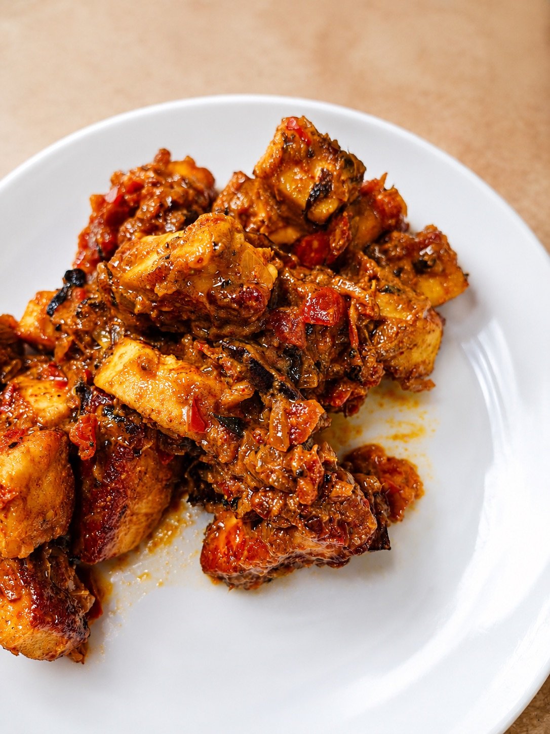 Close-up of masala paneer cubes served on a white plate