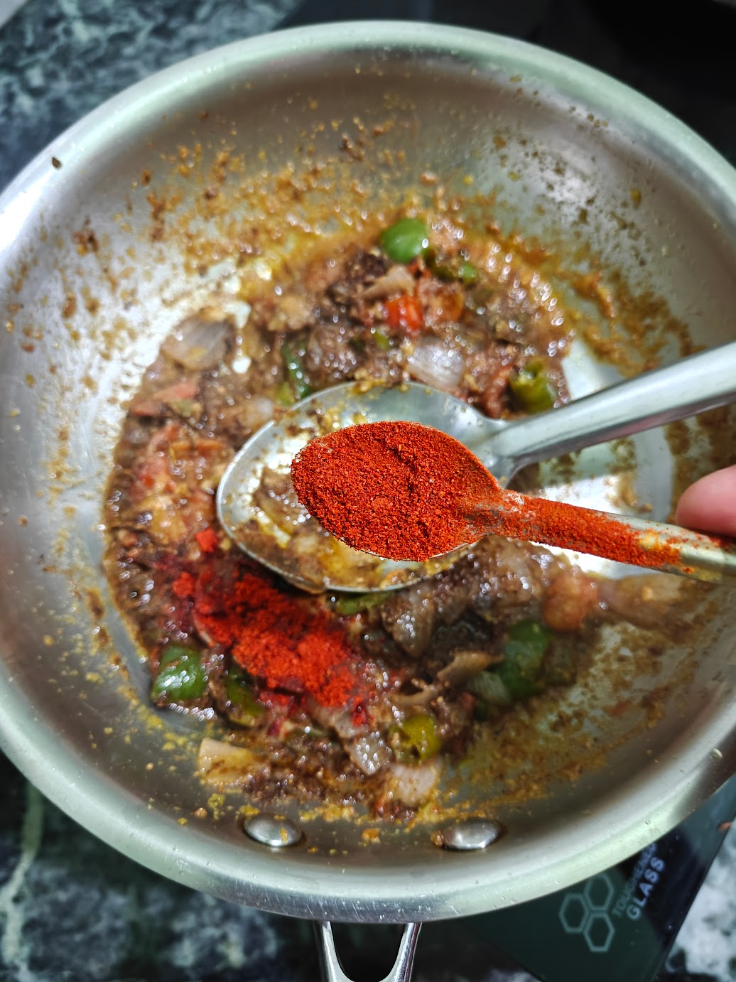 Kashmiri red chilli powder being added to Kadai Paneer gravy