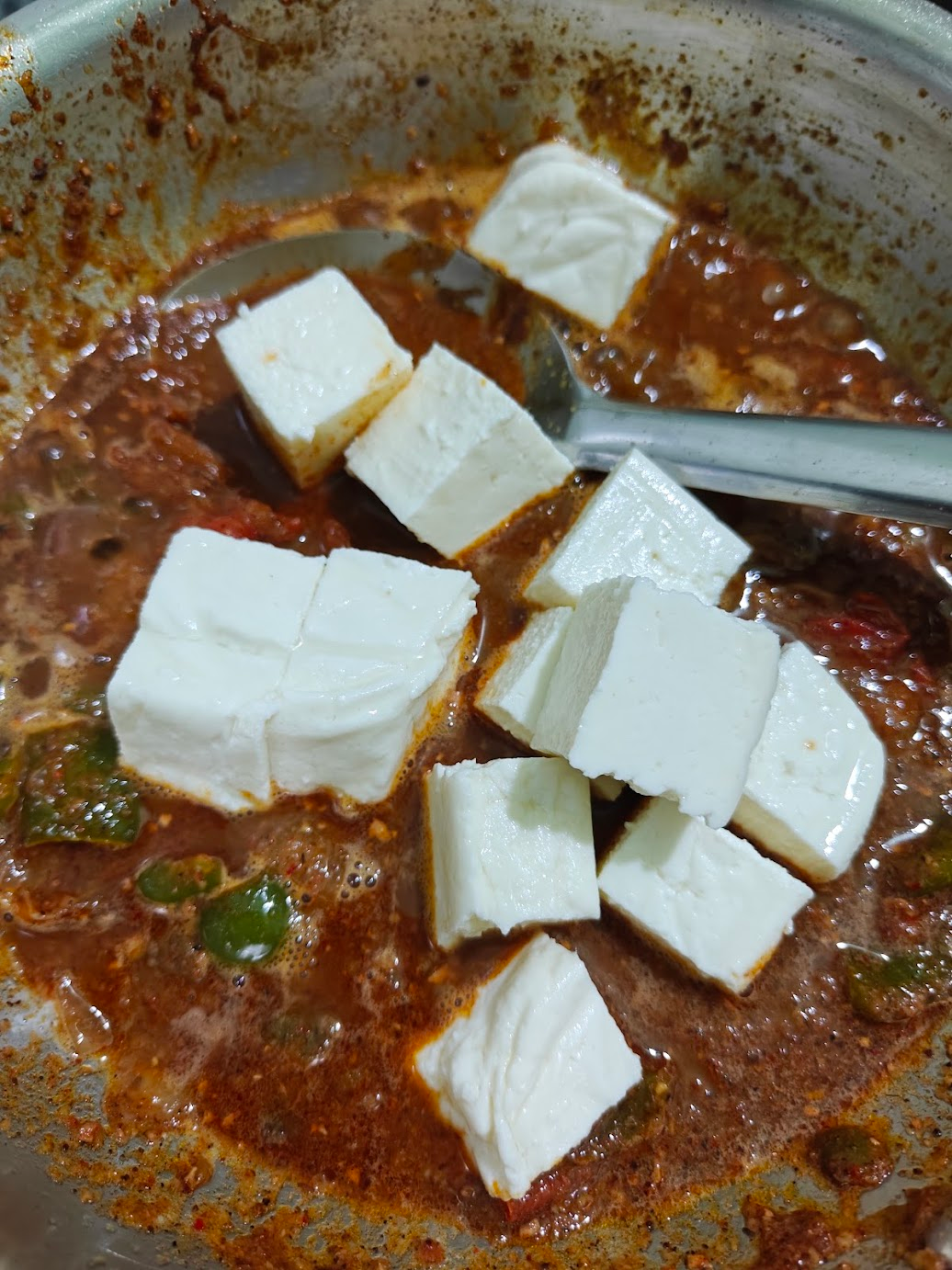 Paneer cubes added to the spicy Kadai Paneer gravy
