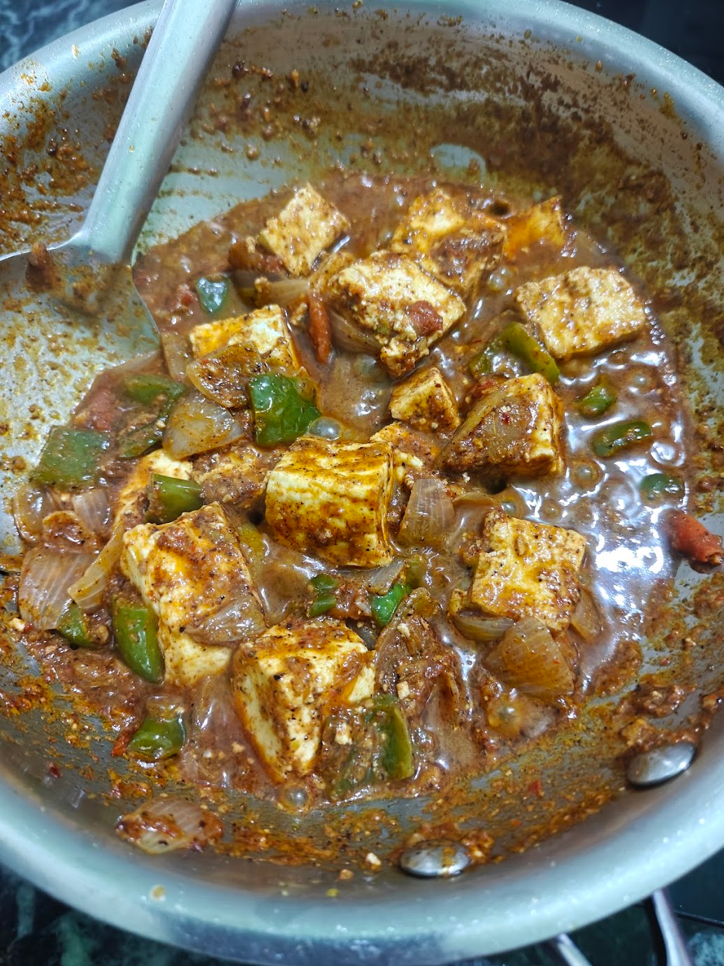 Paneer cubes mixed with onions and green bell peppers in Kadai masala gravy