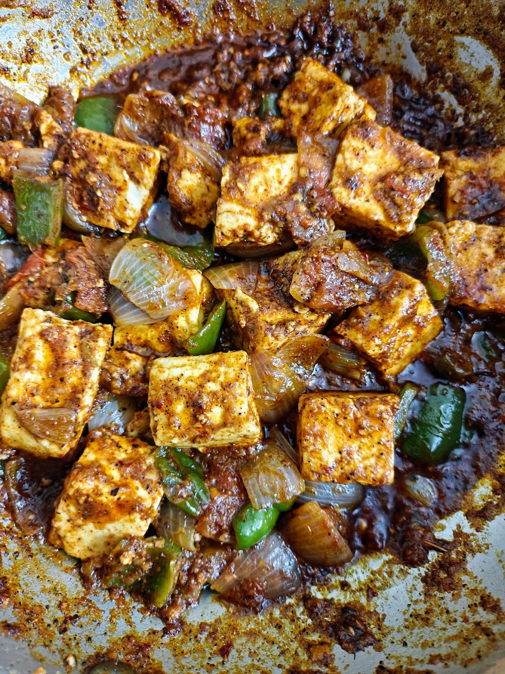 Close-up of homemade Kadai Paneer with paneer cubes, onions and green bell peppers coated in spicy masala