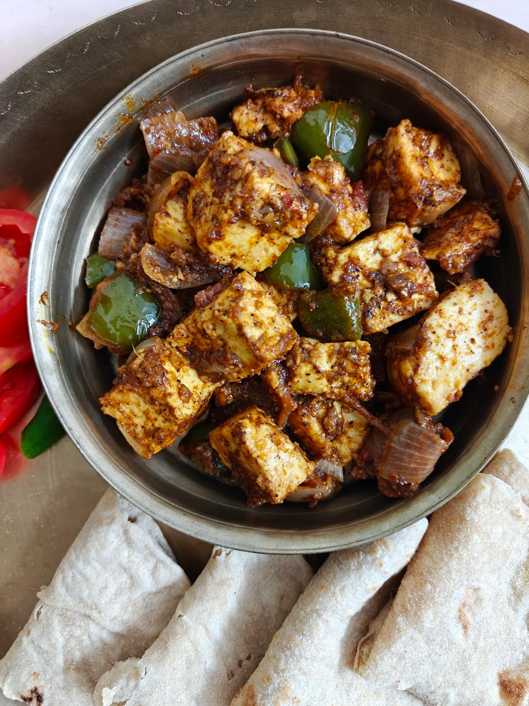 Kadai Paneer served in a bowl with chapatis on the side