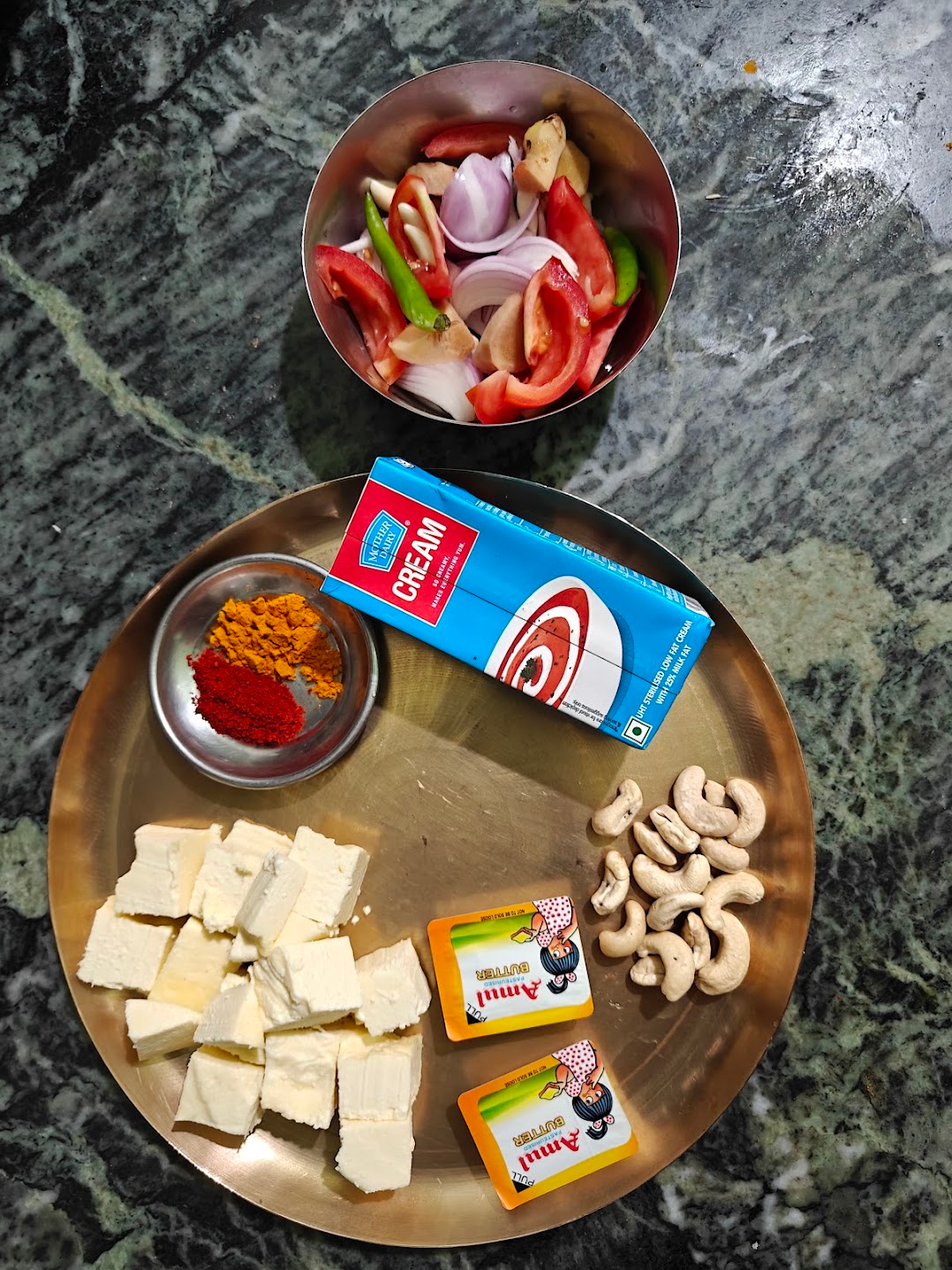 Ingredients for butter paneer, including paneer cubes, tomatoes, onion, ginger, garlic, green chillies, cashews, butter and cream