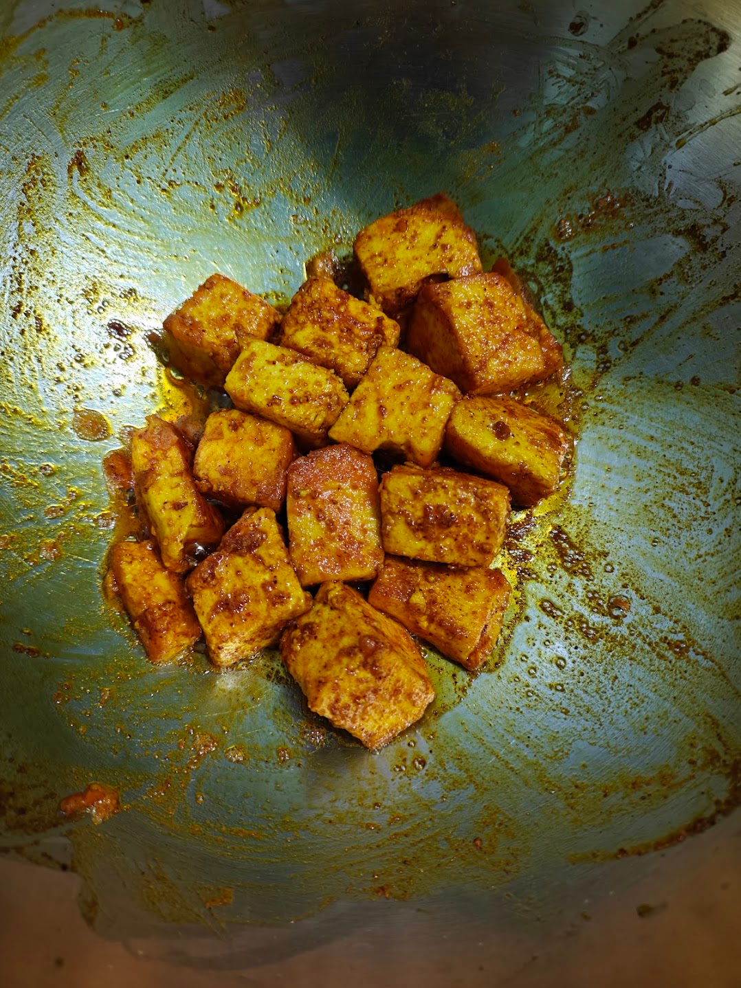 Paneer cubes frying in the pan until golden brown around the edges.