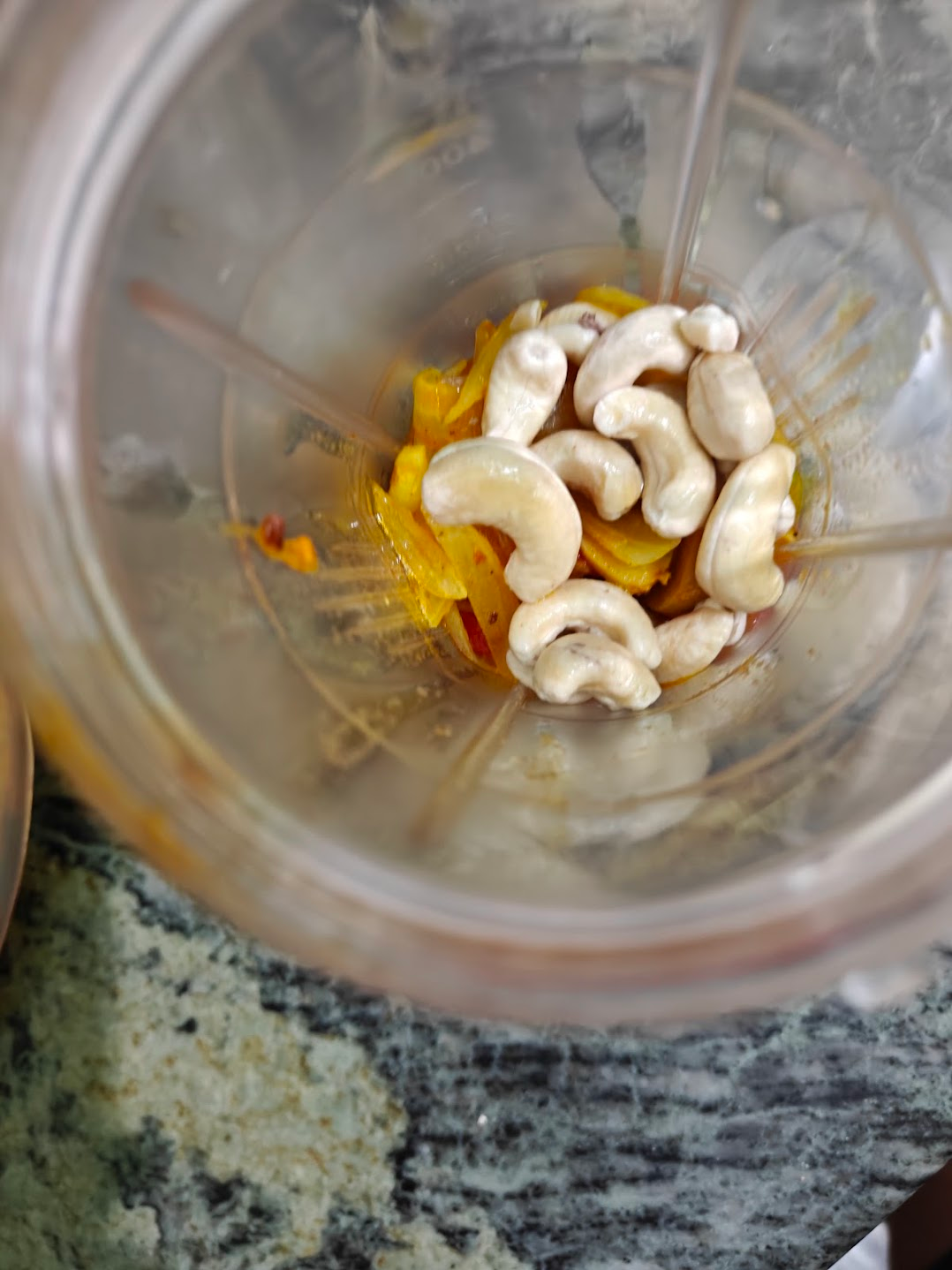 Cooked tomato-onion mixture and soaked cashews placed in a blender jar.