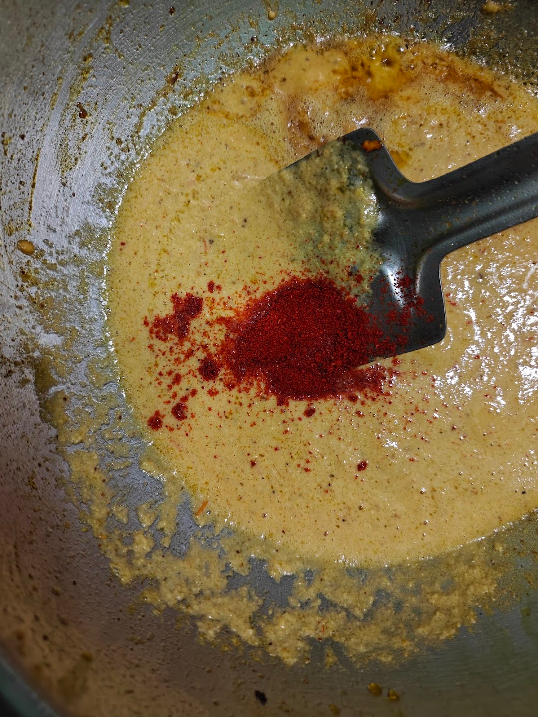 Kashmiri red chilli powder added to the blended tomato-cashew gravy in the pan.