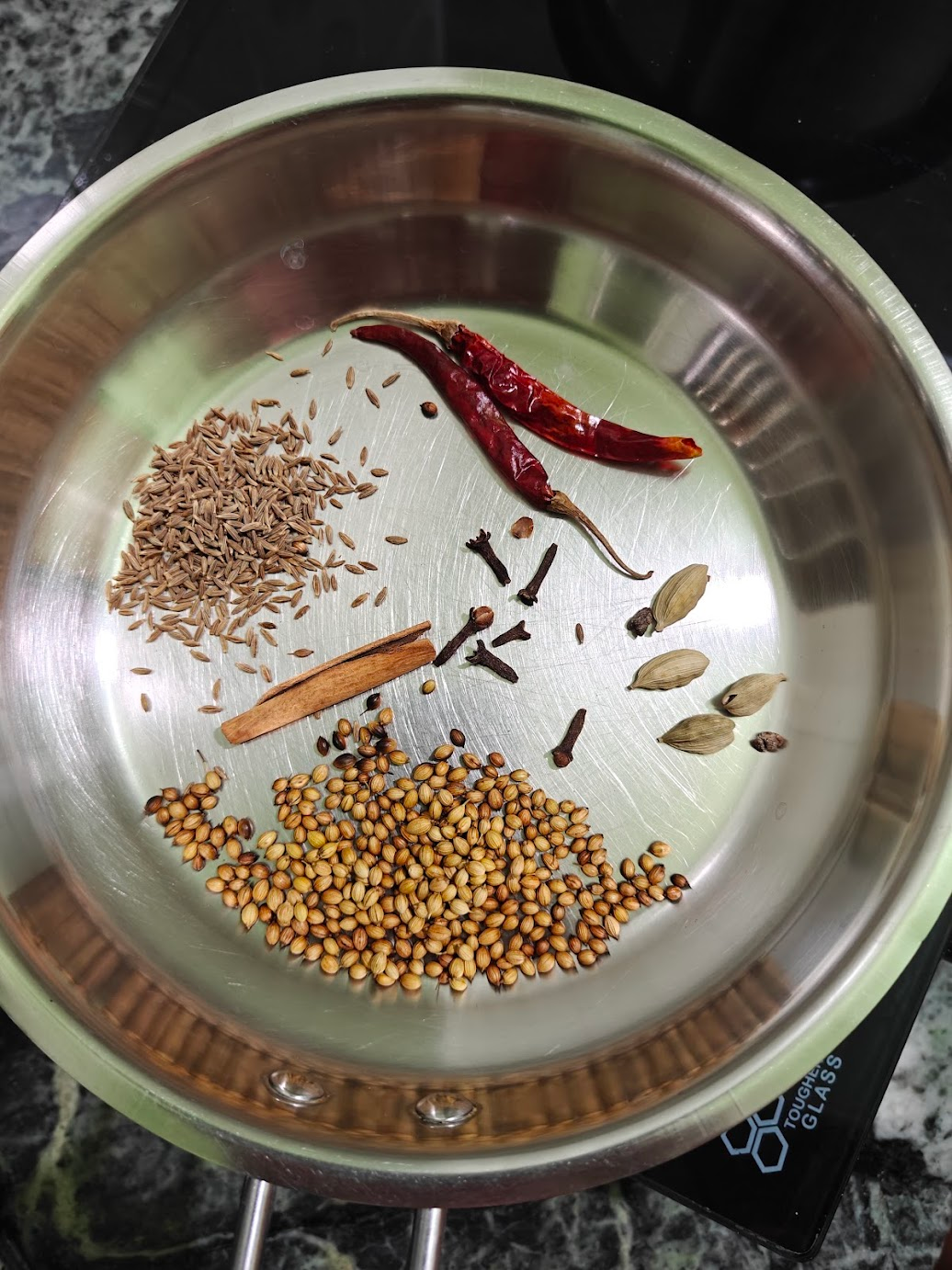 Coriander seeds, cumin seeds, dried red chillies, cinnamon, cloves and cardamom roasting in a pan for Kadai Paneer masala